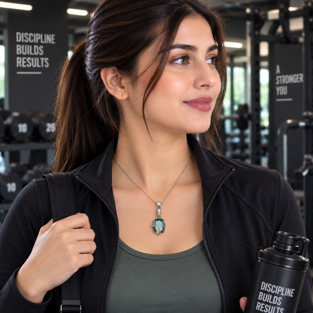 Silver Aqua Teal Oval CZ Solitaire Drop Pendant Necklace worn by model in black gym jacket at gym setting with black gym equipment backdrop