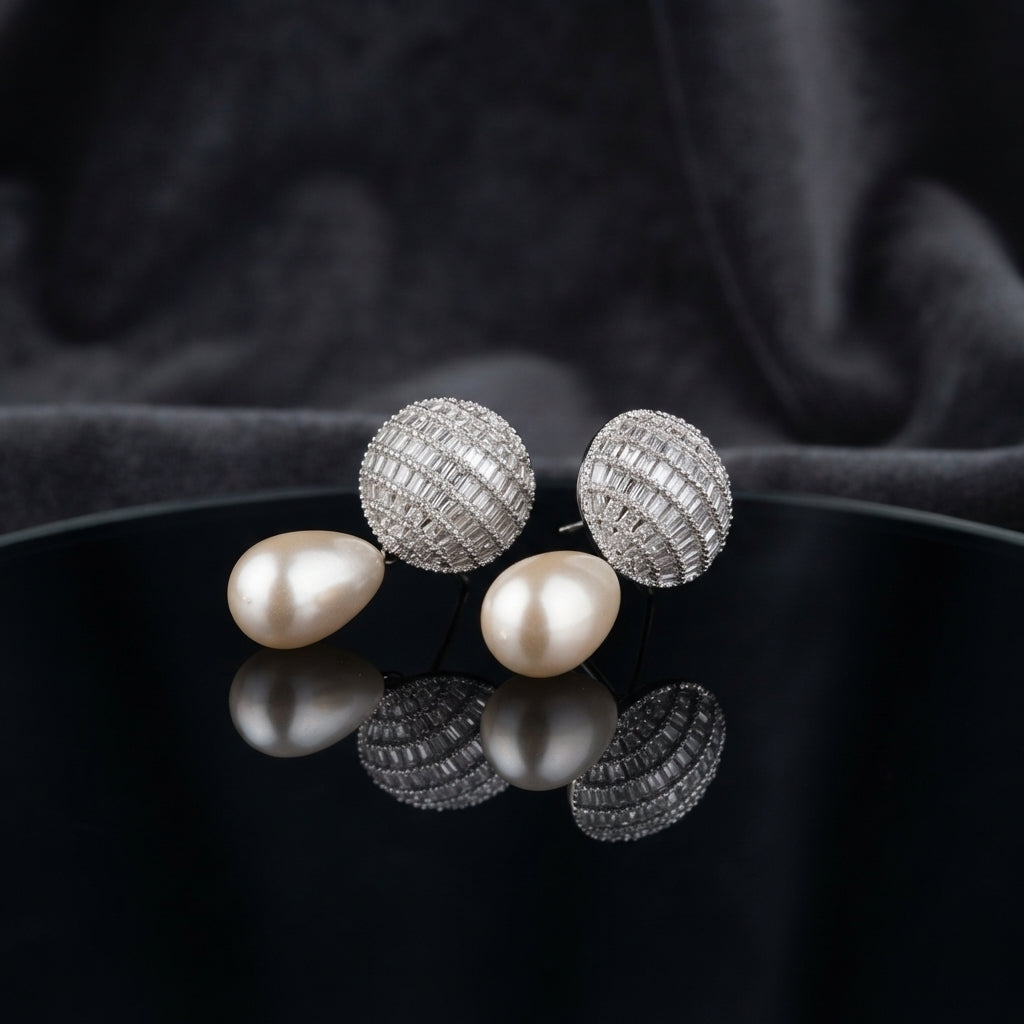 Silver-Tone Baguette CZ Globe Sphere Stud & Pearl Teardrop Drop Earrings on black mirror surface with dark grey silk fabric backdrop