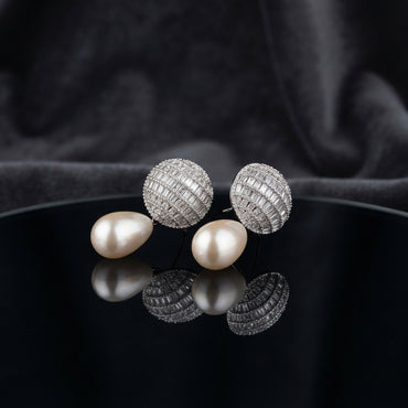 Silver-Tone Baguette CZ Globe Sphere Stud & Pearl Teardrop Drop Earrings on black mirror surface with dark grey silk fabric backdrop