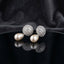 Silver-Tone Baguette CZ Globe Sphere Stud & Pearl Teardrop Drop Earrings on black mirror surface with dark grey silk fabric backdrop