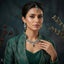 Silver Baguette Fan Scallop CZ Necklace Earrings Tikka Bridal Set in Emerald Green — model wearing rhodium-plated emerald green baguette fan scallop collar necklace with pear CZ center drop, matching chandelier earrings and maang tikka, teal botanical editorial backdrop