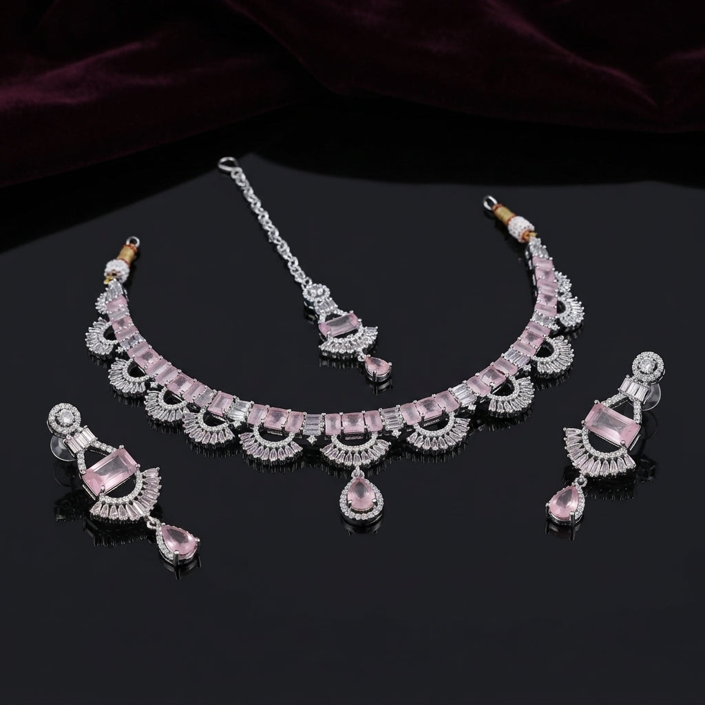 Silver Baguette Fan Scallop CZ Necklace Earrings Tikka Bridal Set in Rose Pink — flat-lay of rhodium-plated 3-piece bridal set: rose pink baguette CZ scallop necklace, chandelier earrings and maang tikka on dark mirror surface with burgundy velvet backdrop
