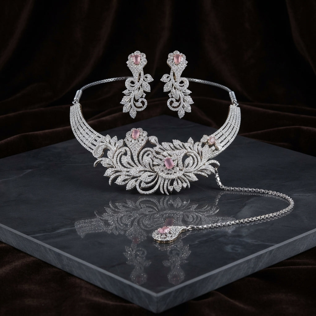 Silver Blush Pink CZ Baroque Floral Scrollwork Torque Necklace Earrings & Maang Tikka Bridal Set on dark grey marble surface with dark brown velvet drape backdrop