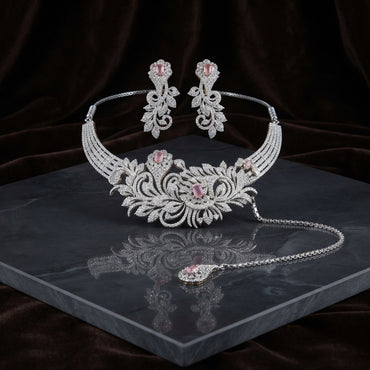 Silver Blush Pink CZ Baroque Floral Scrollwork Torque Necklace Earrings & Maang Tikka Bridal Set on dark grey marble surface with dark brown velvet drape backdrop