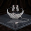 Silver Blush Pink CZ Baroque Floral Scrollwork Torque Necklace Earrings & Maang Tikka Bridal Set on dark grey marble surface with dark brown velvet drape backdrop