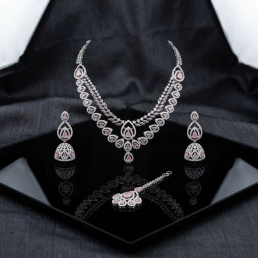 Silver-Tone Blush Pink Pear CZ & White CZ Pavé Lotus Petal V-Necklace Jhumka Earrings & Maang Tikka 3-Piece Bridal Set on black mirror geometric tray with dark grey silk drape backdrop