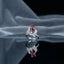 Silver Butterfly Ruby Red Pear CZ Pavé Cocktail Ring — angled 3/4 view: rhodium butterfly ring with ruby-red pear center, full CZ pavé wings, CZ shoulder band, on grey silk fabric with mirror reflection and soft architectural editorial backdrop