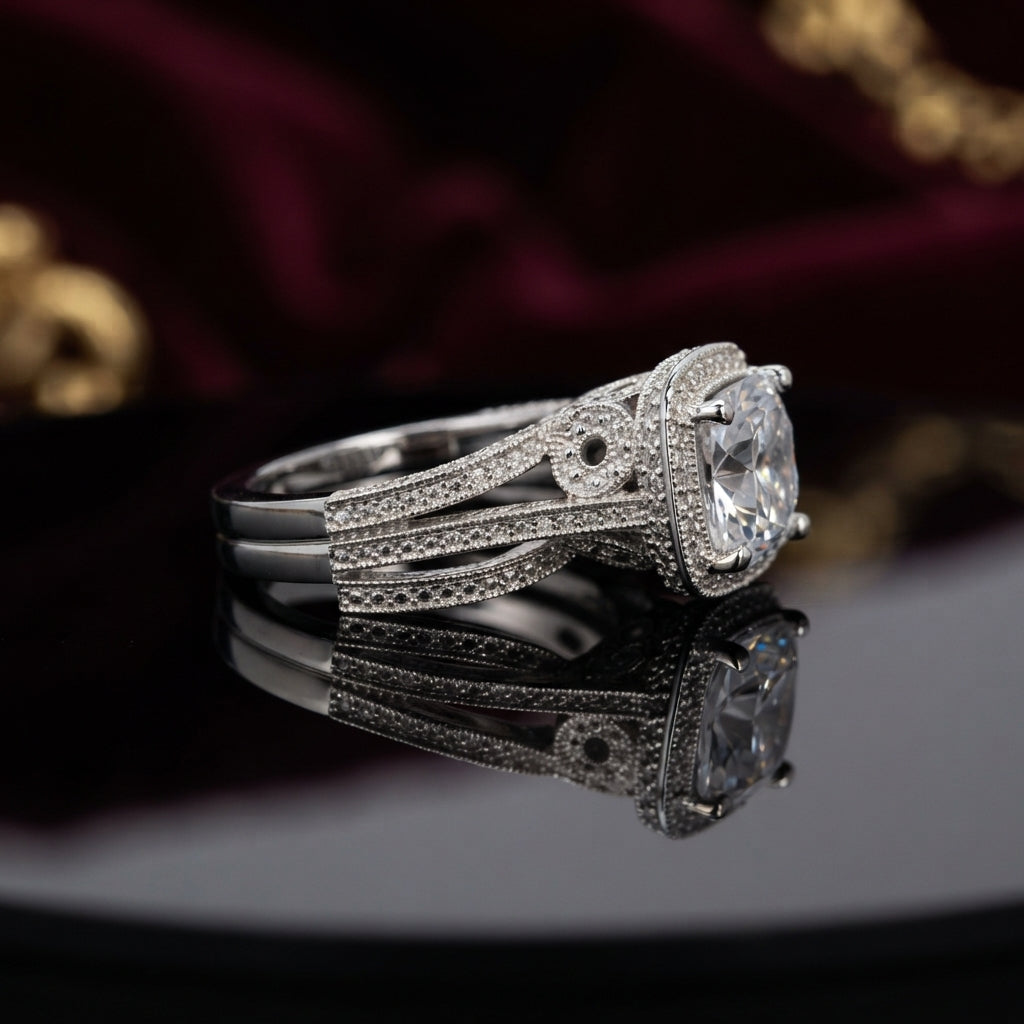 Silver Cushion Cut CZ Halo Art Deco Split Shank Bridal Ring side profile view on dark mirror surface with burgundy velvet and gold jewellery backdrop showing large cushion-cut white CZ solitaire in square micro-pave CZ halo frame with Art Deco triple split shank featuring open scrollwork filigree infinity loop side motifs full micro-pave CZ and milgrain bead edges with mirror reflection below
