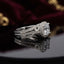 Silver Cushion Cut CZ Halo Art Deco Split Shank Bridal Ring side profile view on dark mirror surface with burgundy velvet and gold jewellery backdrop showing large cushion-cut white CZ solitaire in square micro-pave CZ halo frame with Art Deco triple split shank featuring open scrollwork filigree infinity loop side motifs full micro-pave CZ and milgrain bead edges with mirror reflection below
