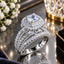 Silver-Tone Cushion Cut CZ Micro-Pavé Double Halo Marquise Petal Triple Split-Shank Pavé Band Bridal Ring on mirror surface with white flowers, crystal candleholder and Destiny jewelry box
