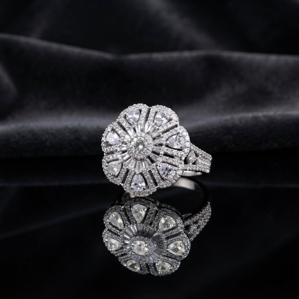 Silver CZ Art Deco Sunburst Flower Pear Petal Pavé Cocktail Ring in White — all-white CZ pear petals and round brilliant center on wide pavé split shank, luxury product shot on black mirror surface with dark charcoal silk backdrop