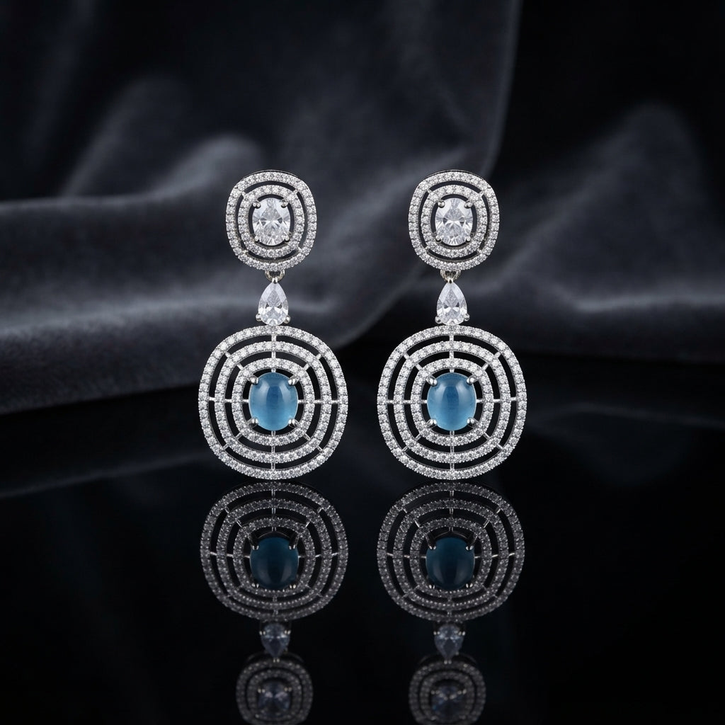 Silver CZ Concentric Orbit Double Disc and Pear Connector Drop Earrings in White Diamond on dark mirror surface with charcoal satin backdrop showing rhodium silver pair with concentric cushion orbit stud white pear connector and large orbit disc pendant with cushion clear white CZ centre solitaire