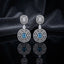 Silver CZ Concentric Orbit Double Disc and Pear Connector Drop Earrings in White Diamond on dark mirror surface with charcoal satin backdrop showing rhodium silver pair with concentric cushion orbit stud white pear connector and large orbit disc pendant with cushion clear white CZ centre solitaire