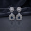 Silver CZ Concentric Orbit Double Disc and Pear Connector Drop Earrings in Aqua Blue on dark mirror surface with charcoal satin backdrop showing rhodium silver pair with concentric cushion orbit stud white pear connector and large orbit disc pendant with oval aqua blue teal cabochon CZ centre