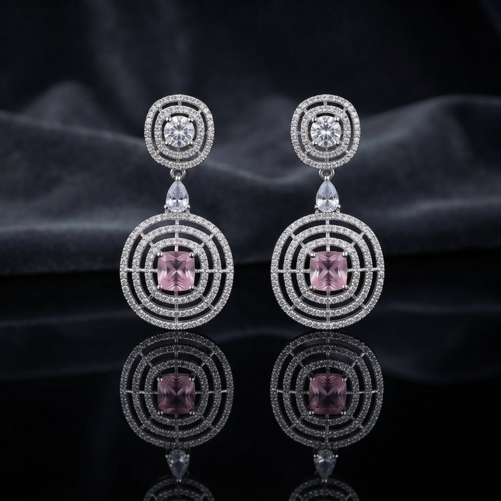 Silver CZ Concentric Orbit Double Disc and Pear Connector Drop Earrings in Emerald Green on dark mirror surface with charcoal satin backdrop showing rhodium silver pair with concentric cushion orbit stud white pear connector and large orbit disc pendant with round brilliant emerald green CZ centre solitaire