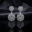 Silver CZ Concentric Orbit Double Disc and Pear Connector Drop Earrings in Navy Sapphire on dark slate surface with charcoal satin backdrop showing rhodium silver pair with concentric circular orbit stud white pear connector and large orbit disc pendant with oval navy sapphire blue CZ centre solitaire