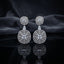 Silver CZ Concentric Orbit Double Disc and Pear Connector Drop Earrings in Rose Pink on dark mirror surface with charcoal satin backdrop showing rhodium silver pair with concentric cushion orbit stud white pear connector and large orbit disc pendant with cushion rose pink morganite CZ centre solitaire