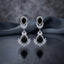 Silver CZ Double Teardrop Cabochon Lotus Fan Chandelier Earrings in Turquoise pair on dark mirror surface showing rhodium-plated small turquoise pear cabochon stud with white CZ pave halo infinity connector and large turquoise pear cabochon drop with white CZ pave halo and marquise CZ lotus fan crown with mirror reflection below