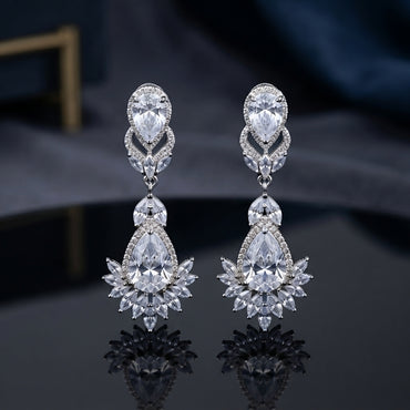 Silver CZ Double Teardrop Cabochon Lotus Fan Chandelier Earrings in Crystal Clear pair on dark mirror surface with navy blue backdrop showing rhodium-plated small crystal clear pear CZ stud with white CZ pave halo infinity connector and large crystal clear pear CZ drop with white CZ pave halo and marquise CZ lotus fan crown with mirror reflection below