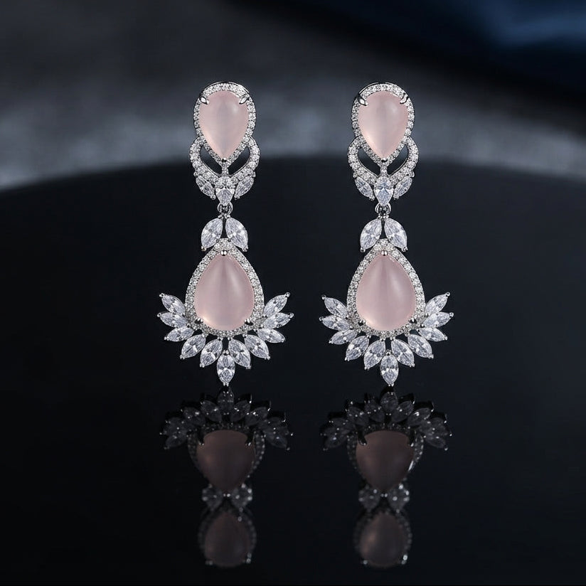 Silver CZ Double Teardrop Cabochon Lotus Fan Chandelier Earrings in Baby Pink pair on dark mirror surface showing rhodium-plated small rose quartz pear cabochon stud with white CZ pave halo infinity connector and large rose quartz pear cabochon drop with white CZ pave halo and marquise CZ lotus fan crown with mirror reflection below
