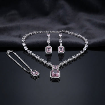 Silver CZ Emerald-Cut Baguette Tennis Necklace Earrings and Maang Tikka Set in Rose Pink on dark charcoal satin surface showing rhodium silver baguette CZ tennis necklace with double rose pink CZ halo pendant matching drop earrings and maang tikka