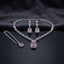 Silver CZ Emerald-Cut Baguette Tennis Necklace Earrings and Maang Tikka Set in Rose Pink on dark charcoal satin surface showing rhodium silver baguette CZ tennis necklace with double rose pink CZ halo pendant matching drop earrings and maang tikka