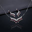 Silver Sapphire Blue CZ Feather Wing V-Bib Necklace and Drop Earrings Set flat lay on dark grey draped fabric showing navy sapphire blue CZ graduating pear drops with white CZ micro-pavé feather wing body necklace and matching earrings with mirror reflection