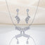 Silver White CZ Feather Wing V-Bib Necklace and Drop Earrings Set flat lay on ivory cream satin backdrop showing all-white diamond illusion CZ V-bib necklace with graduating pear CZ drops and matching feather wing drop earrings with reflection