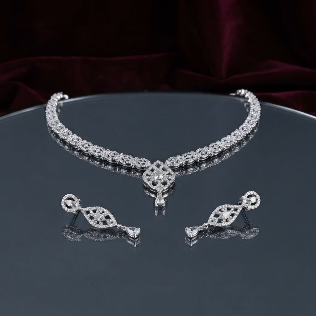 Silver CZ Floral Lattice Choker Necklace and Marquise Teardrop Earrings Bridal Set — rhodium silver-tone 2-piece bridal set with full-coverage continuous CZ micro-pavé floral lattice choker with Gothic arch fleur-de-lis center V-drop and hanging teardrop CZ pendant and matching elongated marquise CZ frame drop earrings displayed on dark mirror round tray with burgundy velvet backdrop