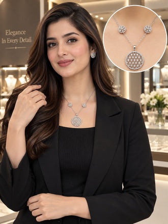 Silver CZ Flower of Life Circle Pendant Necklace and Stud Earrings Set worn by Pakistani female model in black blazer in luxury jewelry boutique backdrop showing large round Flower of Life sacred geometry circle pendant fully covered in dense white CZ micro-pave interlocking petal pattern on fine silver chain with matching round CZ Flower of Life stud earrings with inset product closeup