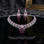 Silver CZ Fringe Choker Starburst Medallion Grand Bridal Parure Set in Ruby Red — rhodium-plated silver-tone 2-piece grand bridal set with wide micro-pavé CZ fringe choker with ruby red oval cabochon stations and starburst medallion center with cascading ruby pear drops, with matching 4-tier ruby red chandelier earrings on dark black mirror luxury editorial backdrop