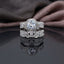 Silver CZ Halo Solitaire Bridal Ring Set 2 Piece angle view on marble surface with white flowers and gold jewellery box backdrop showing round brilliant CZ 6-claw solitaire ring stacked with wide triple-row micro-pave CZ band featuring open filigree arabesque scroll sides in rhodium silver-tone plating