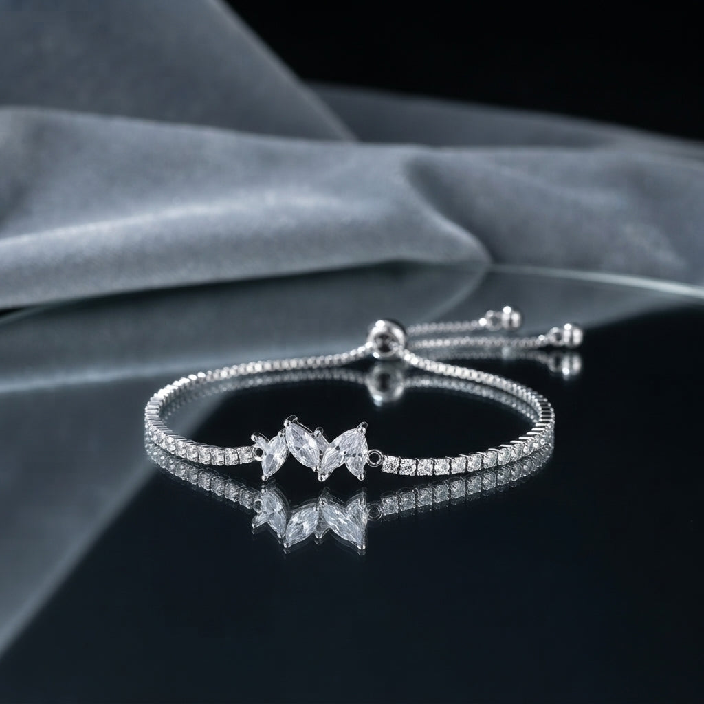 Silver CZ Marquise Leaf Cluster Tennis Adjustable Bracelet — rhodium-plated full tennis bracelet with continuous square CZ band, 3-marquise white CZ fan leaf cluster center motif, and adjustable sliding ball closure, on dark mirror surface with grey silk fabric backdrop