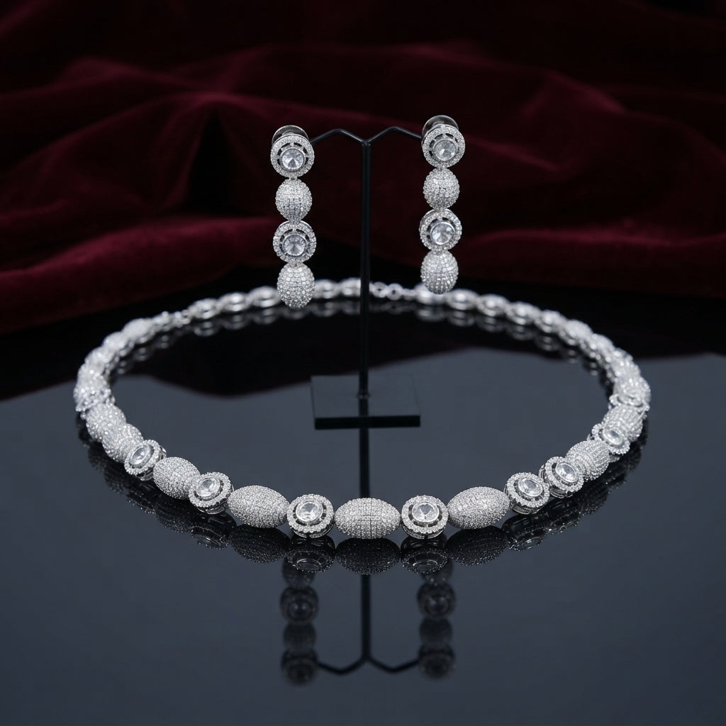 CZ Micro-Pavé Ball Disc Choker Necklace Earrings Set in Silver — flat-lay of full rhodium-plated choker collar and 4-drop earrings on dark mirror surface with deep burgundy velvet backdrop, earrings displayed on black T-bar stand