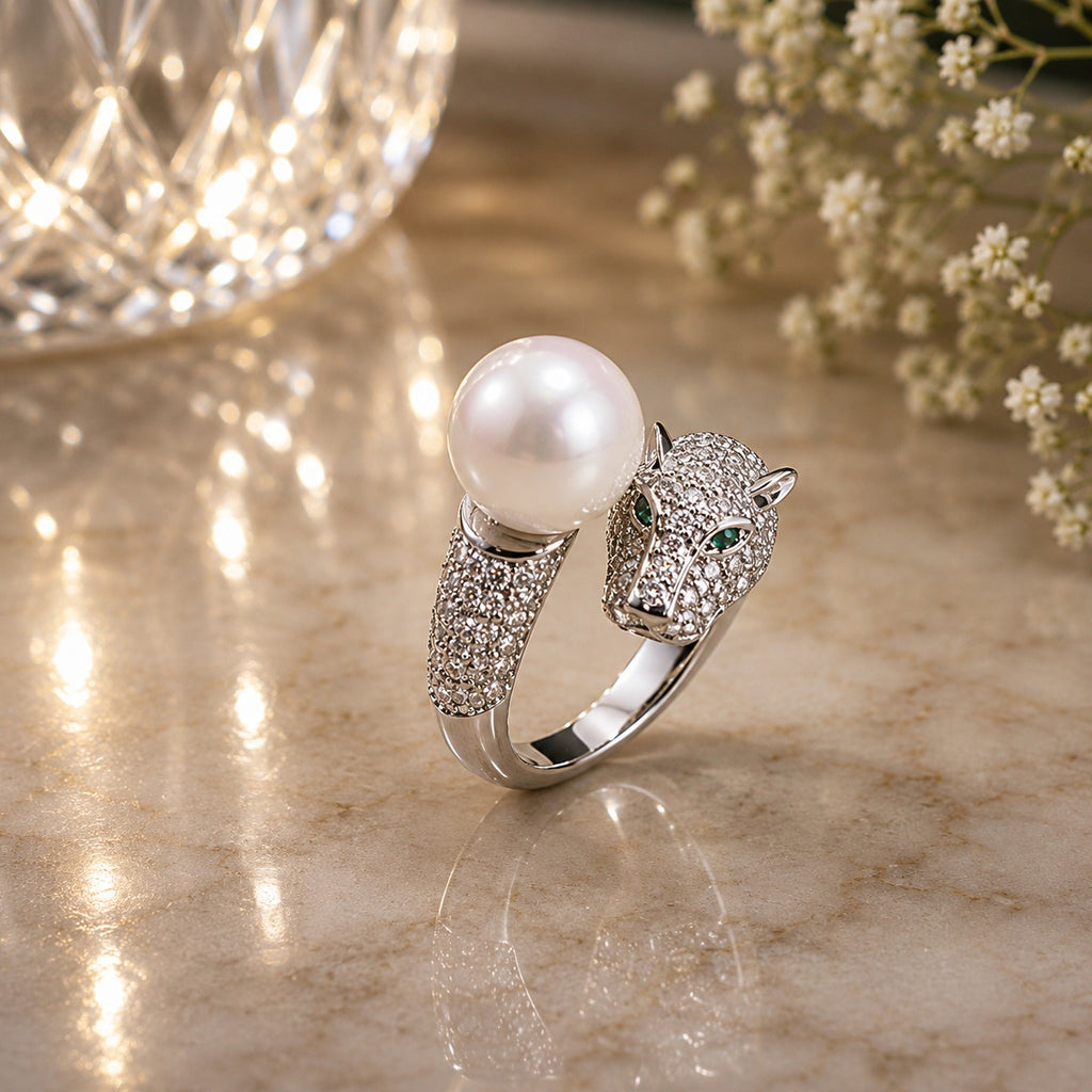 Silver-Tone CZ Pavé Panther Head & Pearl Bypass Open Cocktail Ring on cream marble surface with crystal bokeh light orb and white baby’s breath flowers backdrop