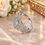 Silver CZ Peacock Feather Plume Halo Open Cuff Cocktail Ring on cream marble surface with white roses and gold jewelry tray backdrop