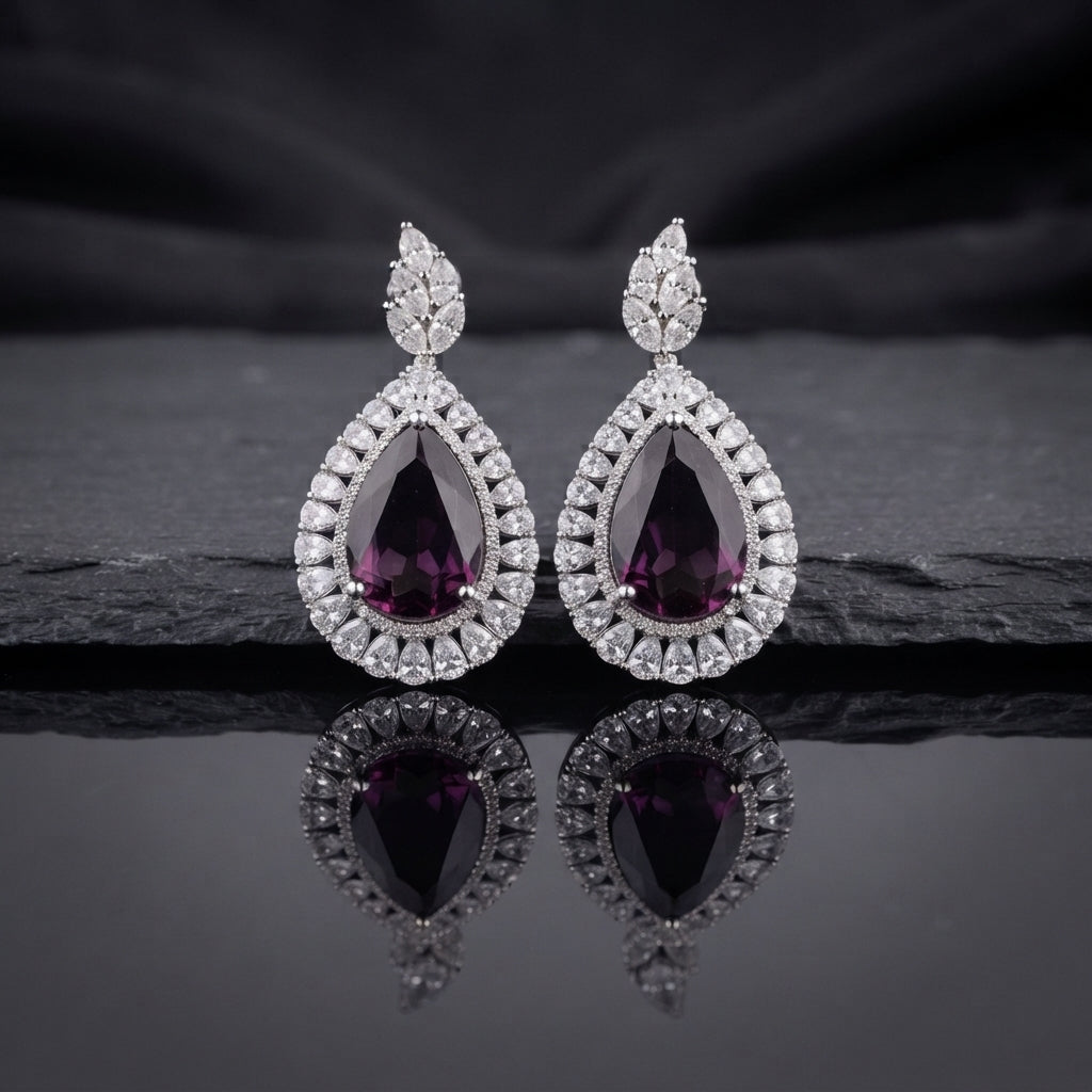 Silver AD Teardrop Halo Drop Earrings in Emerald Green pair on dark slate mirror surface with dark silk backdrop showing rhodium-plated marquise AD leaf cluster stud top and large open pear teardrop frame with baguette triangular AD halo border and deep emerald green faceted pear AD centre stone with mirror reflection below