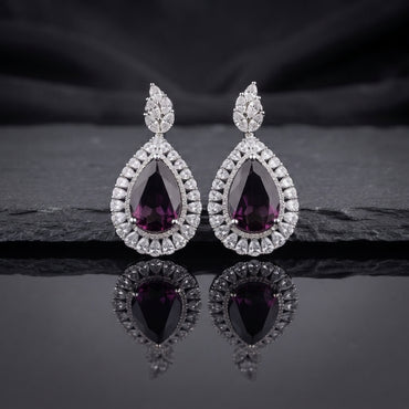 Silver AD Teardrop Halo Drop Earrings in Emerald Green pair on dark slate mirror surface with dark silk backdrop showing rhodium-plated marquise AD leaf cluster stud top and large open pear teardrop frame with baguette triangular AD halo border and deep emerald green faceted pear AD centre stone with mirror reflection below