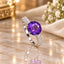 Silver Deep Amethyst Oval CZ Solitaire Multi-Row Pavé Shoulder Cocktail Ring on cream marble surface with white flowers and gold jewelry box backdrop