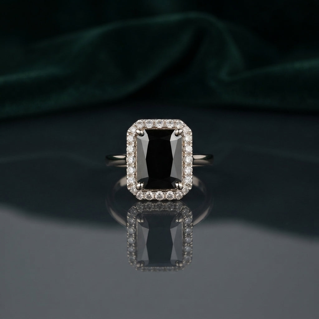 Silver Emerald Cut CZ Rectangular Halo Pave Band Solitaire Ring in Emerald Green variant on dark mirror surface with charcoal satin backdrop showing rich deep emerald green emerald-cut CZ solitaire in 4-claw setting with full rectangular white CZ halo and continuous micro-pave white CZ band in rhodium silver with mirror reflection below