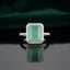 Silver Emerald Cut CZ Rectangular Halo Pave Band Solitaire Ring in Sapphire Blue variant on dark mirror surface with dark teal velvet backdrop showing deep royal sapphire blue emerald-cut CZ solitaire in 4-claw setting with full rectangular white CZ halo and continuous micro-pave white CZ band in rhodium silver with mirror reflection below