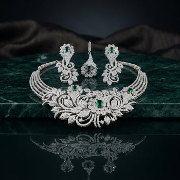 Silver Emerald Green CZ Botanical Floral Garden Statement Necklace & Earrings Bridal Set on dark green marble surface with grey silk drape backdrop