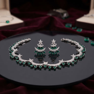 Silver Emerald Green CZ Crescent Moon Star Choker Necklace Earrings Set on black mirror display tray with burgundy velvet backdrop and scattered emerald green CZ stones showing rigid collar choker with repeating crescent moon motifs in emerald green oval round CZ and micro-pave white CZ with marquise star flower connectors and matching crescent moon drop earrings with graduated emerald green CZ fan and star marquise white CZ stud top with mirror reflections below
