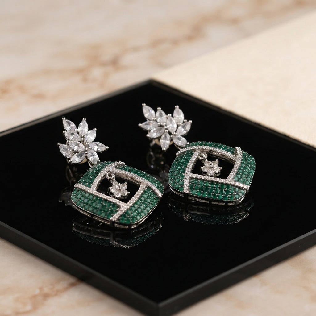 Silver Emerald Green CZ Cushion Pavé and White CZ Marquise Lotus Drop Earrings flat lay on mirror surface with marble backdrop showing pair detail with reflection of marquise lotus stud and emerald green CZ cushion pavé drop with white CZ cross grid overlay
