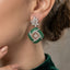 Silver Emerald Green CZ Cushion Pavé and White CZ Marquise Lotus Drop Earrings worn by model in emerald green velvet top showing full marquise white CZ lotus spray stud and large emerald green CZ cushion pavé drop with white CZ cross grid overlay and suspended flower charm