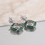 Silver Emerald Green CZ Cushion Pavé and White CZ Marquise Lotus Drop Earrings flat lay on black tray with marble backdrop showing pair detail of marquise lotus stud and dense emerald green CZ cushion drop with white CZ cross grid and flower charm