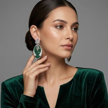 Silver Emerald Green CZ Oval Cluster and Pearl Vine Twisted Leaf Grand Drop Earrings flat lay on ivory cream fabric backdrop showing pair detail of white CZ marquise lotus stud and massive twisted leaf drop with dense oval emerald green CZ cluster face white CZ micro-pavé outer frame and pearl vine overlay