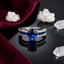 Silver & Gold Two-Tone Oval Sapphire Blue CZ Solitaire, Blue CZ Channel & White CZ Pavé Triple Split-Shank Bridal Ring on black mirror surface with white crystal quartz clusters and deep burgundy velvet backdrop