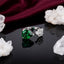 Silver-Tone Heart Emerald Green CZ & White CZ Floral Cluster Toi et Moi Open Adjustable Ring on black mirror surface with white crystal quartz clusters and deep burgundy velvet backdrop