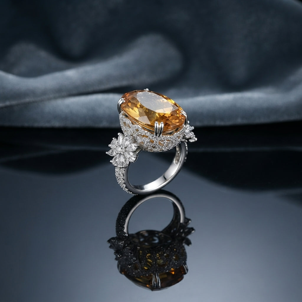 Silver Imperial Citrine Oval CZ Pavé Halo Flower Shoulder Cocktail Ring — dramatic angled side view: rhodium-plated ring with massive golden honey citrine oval center, full CZ micro-pavé halo, twin 5-petal CZ flower shoulders, and pavé band, on dark mirror surface with grey silk fabric backdrop